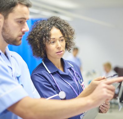 Two nurses work together at a digital tablet